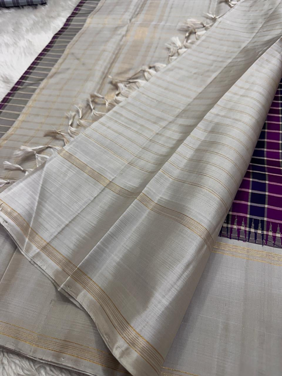 Nirai Navy - A Jewel Toned Checkered pure silk Kanchipuram saree in navy, purple, magenta, and grey checks.Accented with a soft silver-grey border and zari-striped seer pallu
Includes a silver blouse fabric with gold zari stripes