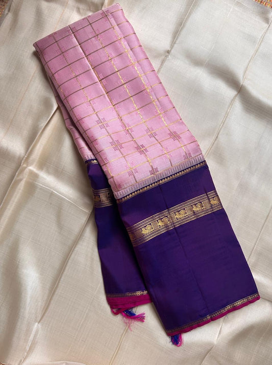 Anaar ✨ – Royal Purple & Lotus Pink Kanchipuram Pure Silk Saree
With Zari Kattam Checks, Mayil Motif Border & Grand Pallu
Korvai Contrast Weave in Regal Purple , 
Peacock & Floral Zari Panels, Raspberry Selvedge Finish
Silk Mark Certified
