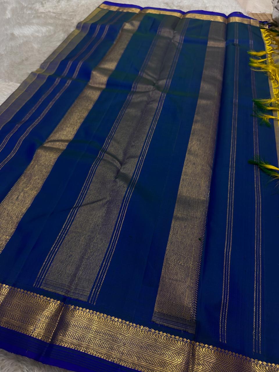 Varnam – Dove Tail Gray & Peacock Blue Kanchipuram Silk Saree. Featuring rich gold paisley buttas, a bold chevron zari border, and pure handloom silk craftsmanship ✨ Silk Mark Certified | Blouse Stitching Available | Free USA Shipping