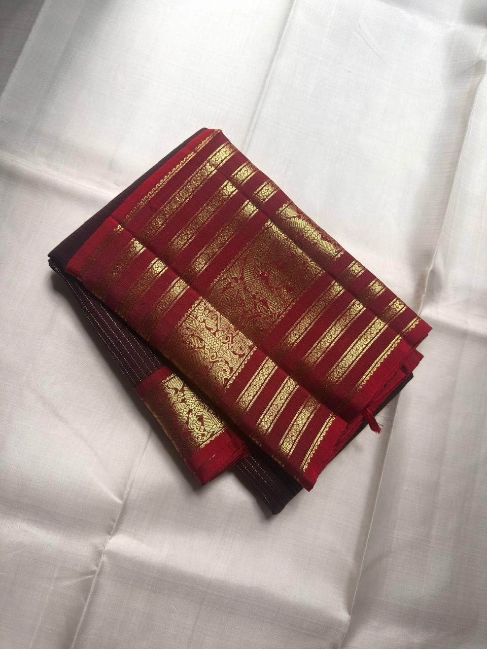 Deep plum Kanchipuram silk body with close-set antique gold oosivaanam lines and spaced gold buttas