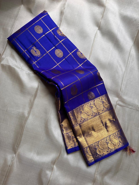 Kalyana Neelam Kattam — Kanchipuram Pure Silk

Deep royal neelam blue body with kattam (grid) checks & mayil buttas

Grand gold kaddi border with ornate paisley vines; rich zari pallu

Silk Mark Certified | Free Shipping within USA

Dispatch in 1 Week
