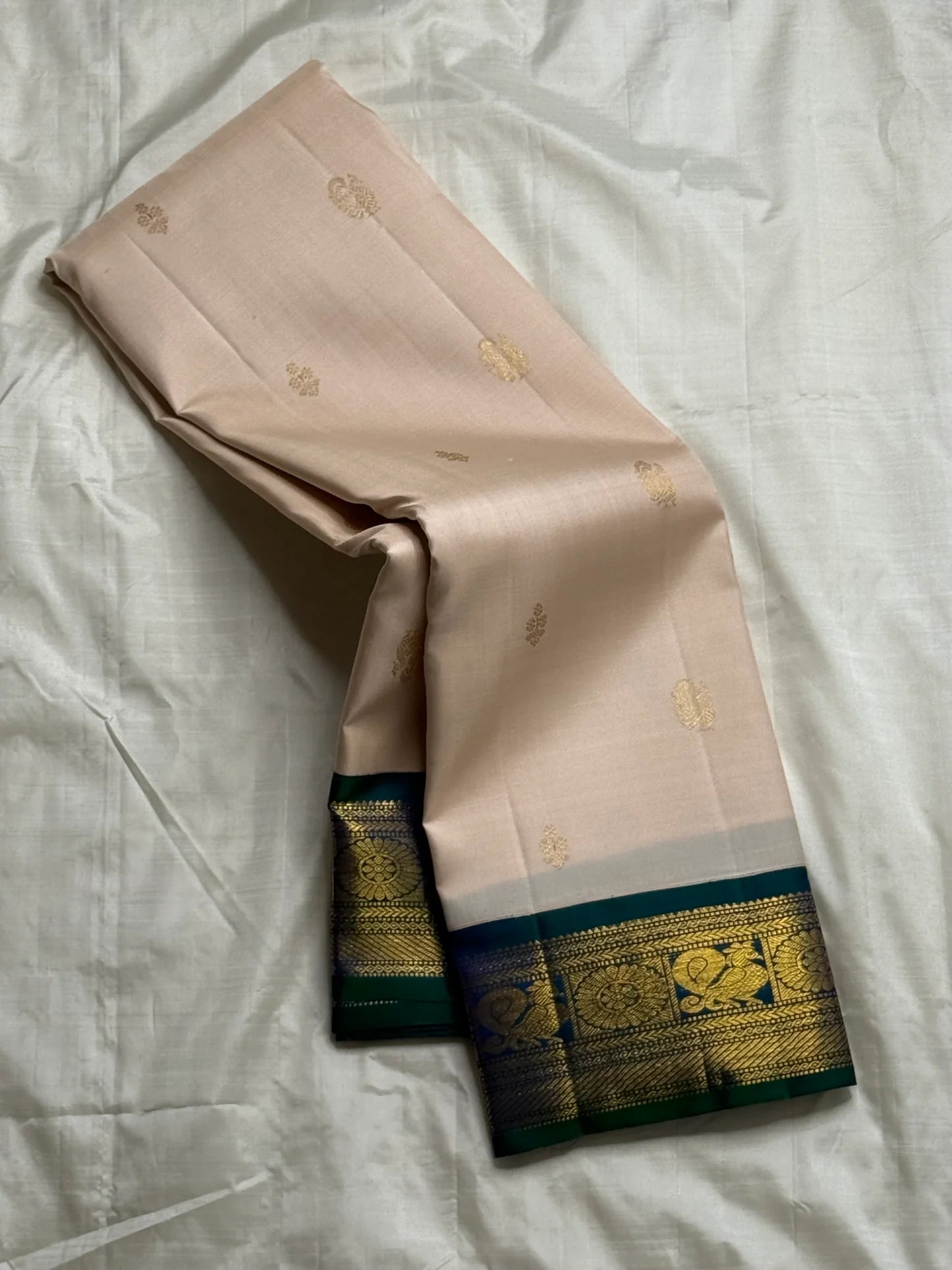 Mayilkazhuthu Shwetham — Pure Kanchipuram Silk Saree
Soft Ivory-Blush Body with Gold Zari Buttas & Peacock Blue-Green Border
Silk Mark Certified • Free Shipping within USA • Ships in Two Weeks