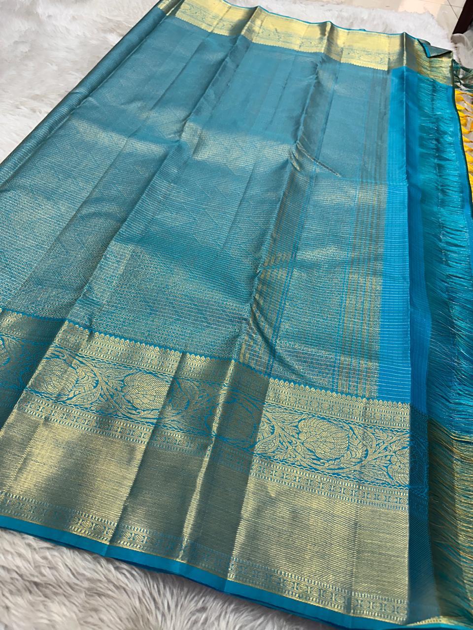 This radiant yellow pure silk drape is elevated by an exquisite and unexpected pairing — a serene sky blue border, making it both eye-catching and rare. Fine zari checks shimmer gently across the body, timeless bavaanji border