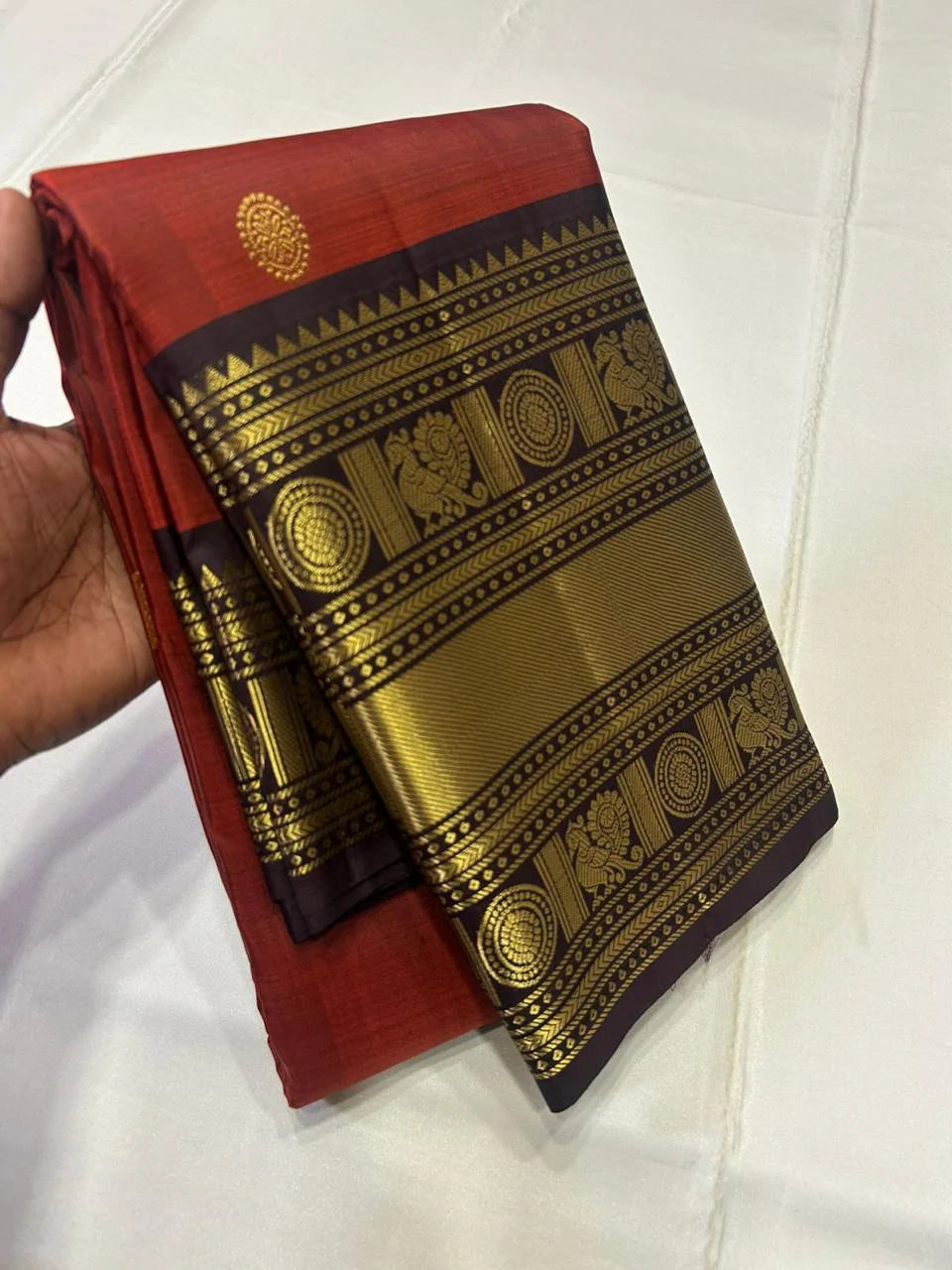 Aruna Mayil – Pure Korvai Kanchipuram Silk Saree

Brick red body with zari rosette buttas

Grand coffee-brown korvai border & pallu with peacock panels, medallions & temple teeth in rich gold zari

Silk Mark Certified | Blouse Piece Included | Fall & Pico