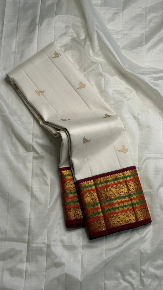 Parakkum Kili — Ivory Pure Silk Kanchipuram

Ivory body with fine zari coin buttas ✨
Rust-orange korvai borders with mayil & temple motifs 🌸
Grand rust-orange zari brocade pallu with tassels 🪔
Silk Mark Certified • Free Shipping USA • Ships in Two Weeks