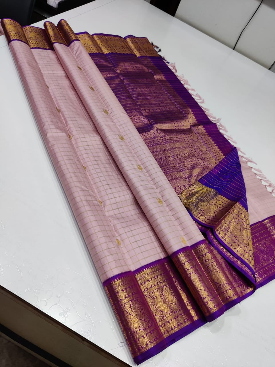 Gilded Blush

 Blush Pink Kanchipuram Pure Silk Saree

All-Over Gold Zari Kattam Weave with Buttas

Royal Purple Border with 2G Zari Peacock Motifs

Grand Purple Brocade Pallu | Contrast Blouse fabric 

 Silk mark certified pure silk , 2G Zari