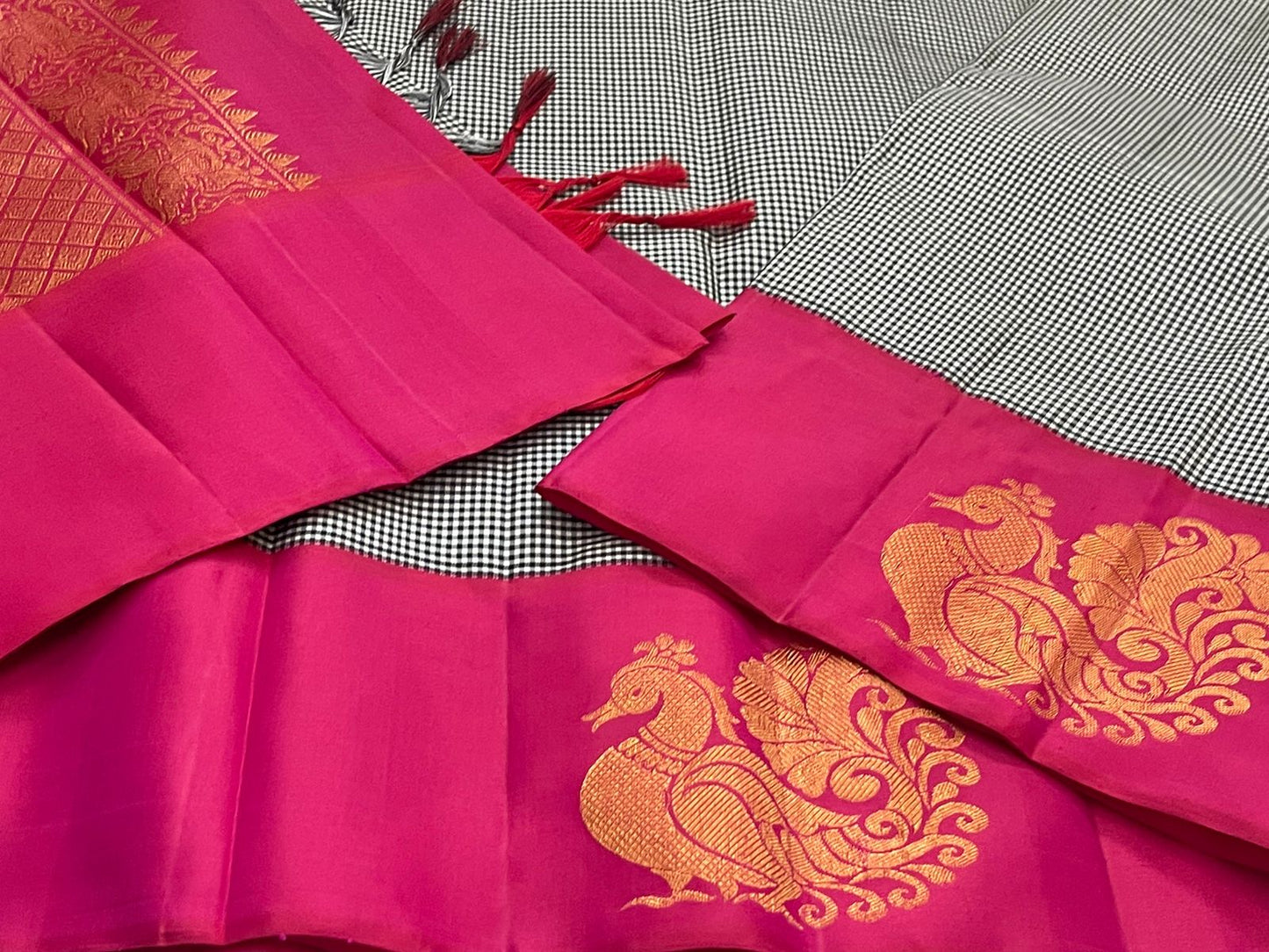 Aaradhana Kattam — Pure Kanchipuram Silk Saree (Black & White × Rani Pink)
Classic black-and-white micro checks with rich rani-pink korvai borders and zari peacock motifs
Silk Mark Certified • Fall & Pico Done • Blouse Stitching Available ($30) • Free Shi