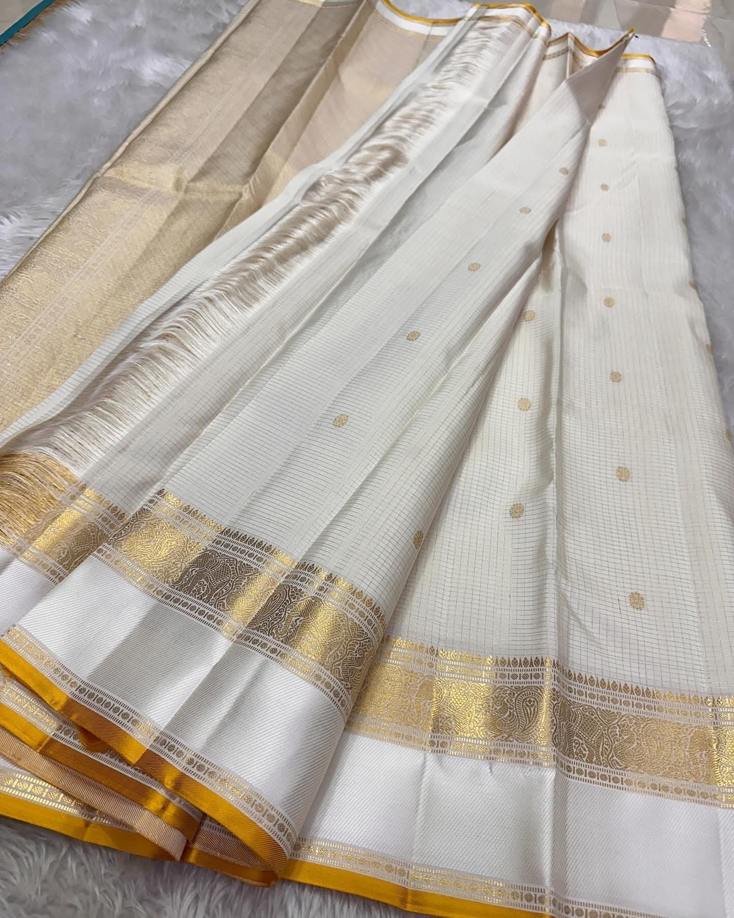 Kiran ivory whiteb oosi kattam  ✨ – ivory and gold  Kanchipuram Pure Silk Saree
Korvai Gold Zari Border with Elephant & Floral Motifs
Body Woven in Zari Kattam Checks with Scattered Gold Buttas
Grand Zari Brocade Pallu | Silk Mark Certified |