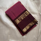 Folded maroon Kanchipuram silk saree with contrast coffee border and gold zari woven detailing