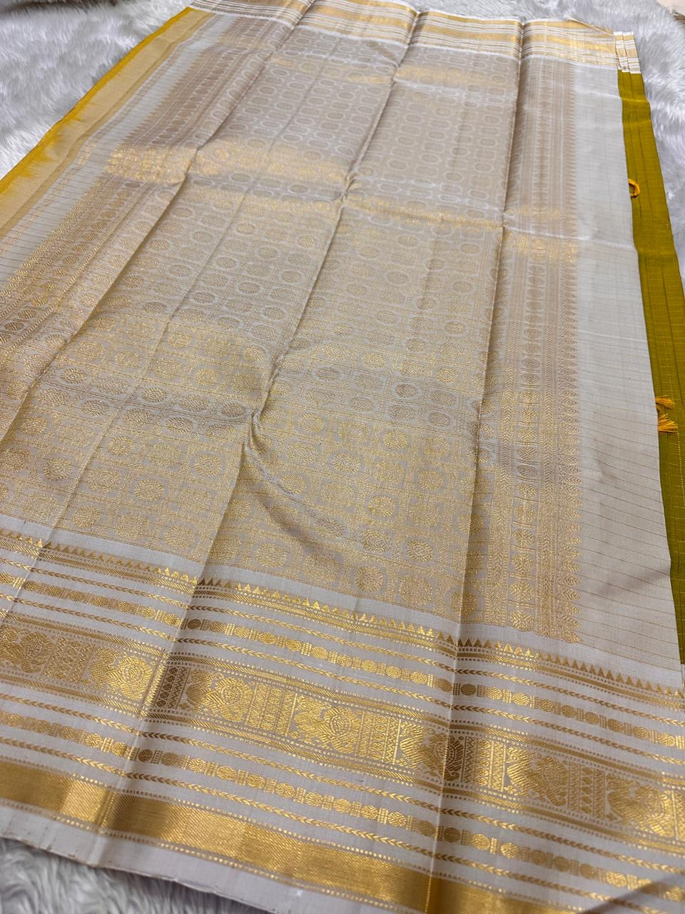 Luminous Lemon-Olive Green — White Korvai Kanchipuram

Pure Silk | Vairaoosi Checks | Korvai Contrast Borders

Classic White & Gold Pallu with Coin Jaal Motifs

Perfect for Muhurtham, Haldi & Temple Occasions

Silk Mark Certified | Free Shipping | Shi