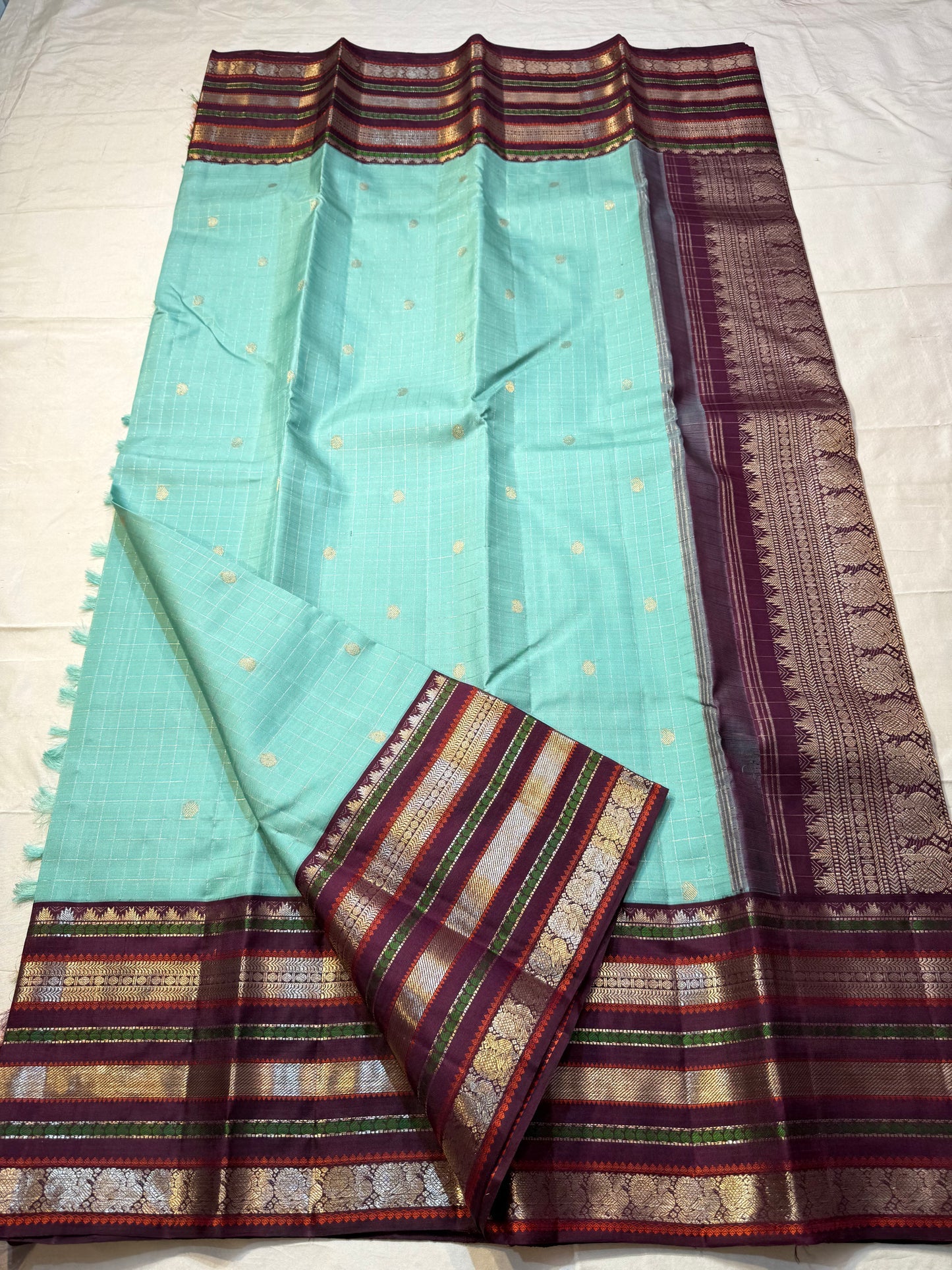 Teal Mint Muthu Kattam — Pure Silk Kanchipuram Saree
Teal-mint body with tiny  zari  buttas & plum-maroon korvai borders
Silk Mark Certified • Free USA Shipping • Ships in Two Weeks