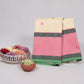 Folded ivory and lotus pink no-zari Kanchipuram silk saree with green silk-thread border, styled with flowers and jasmine on a white backdrop