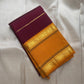 Folded deep maroon pure Kanchipuram silk saree with mustard gold zari border, shown on a light fabric background.