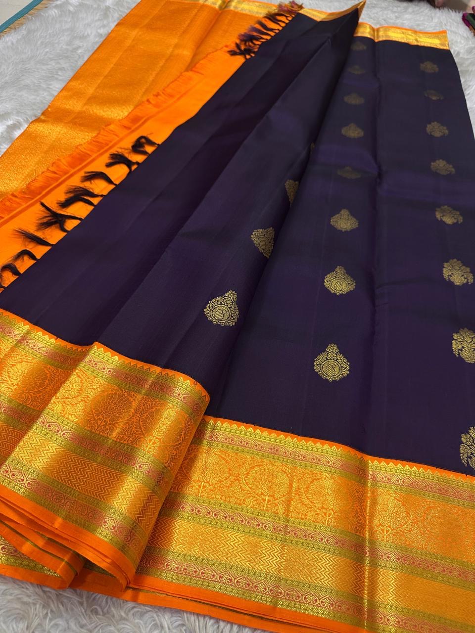 Jamun Purple Kesar – Korvai Kanchipuram Pure Silk Saree

Regal jamun-purple body adorned with antique-gold floral buttas

Kesari-orange korvai border with chakra roundels, vines & chevron zari

Free shipping withinUSA silk mark certified ships in 2 weeks