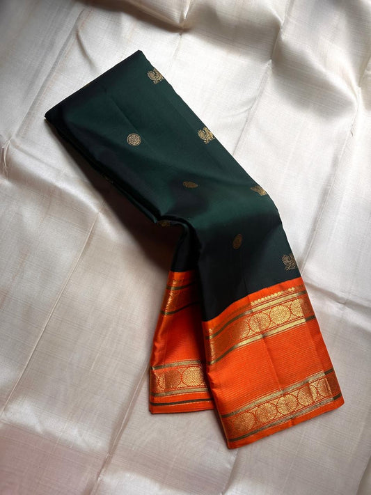 Nirupama ✨ – Bottle-Green Kanchipuram Pure Silk Saree
With Striking Saffron-Orange Korvai Contrast Border rettapet 
Adorned with Gold Rosette Buttas & Medallion Bands
Grand Zari Brocade Pallu in Cascading Motifs
