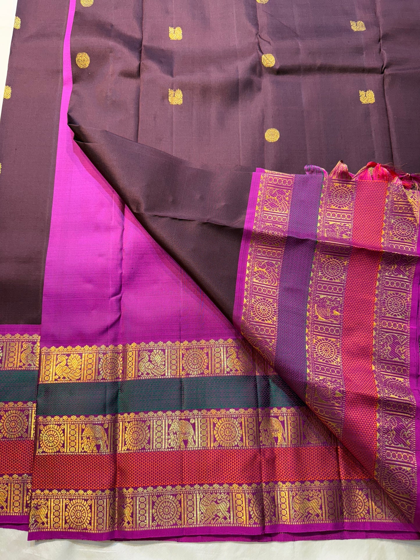 Coffee Brown Rajam – Pure Kanchipuram Silk Saree
Coffee Brown Body with Gold Zari Buttas
Rani Pink Korvai Borders with Temple, Peacock & Elephant Motifs
Grand Rani Pink Zari Brocade Pallu with Vertical Stripes & Tassels
Silk Mark | ships in two weeks