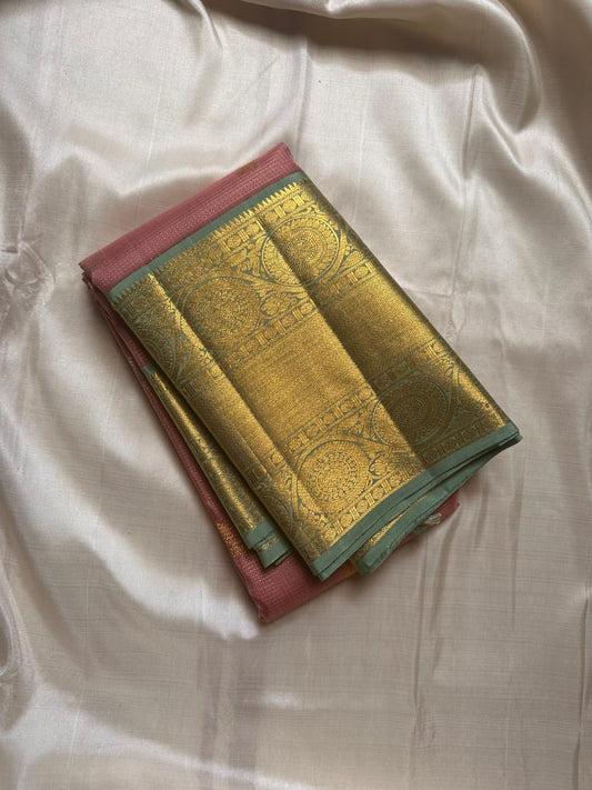 Vahini – Pleasant Peach Pink Pure Kanchipuram Silk Saree with Zari Kattam Checks, Silver & Gold Peacock Buttas, Sage Green Border Adorned with Kamalam Vines and Baavanji Motifs, and an Ornate Zari Pallu with Majestic Peacocks
