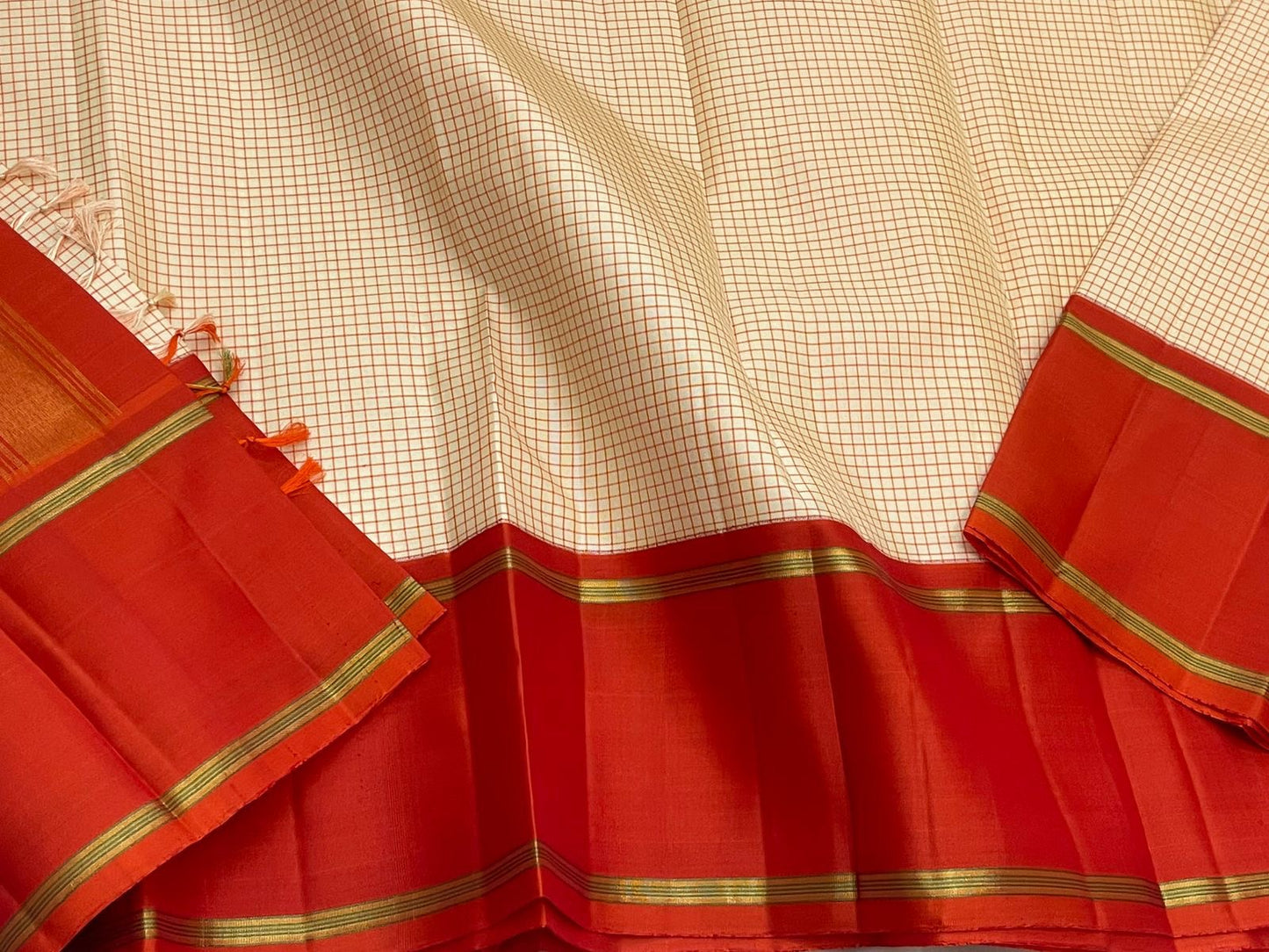 Ivory Vermillion Kattam — Pure Silk Kanchipuram Saree
Buttermilk-Ivory Body with Red Micro-Checks & Vermilion Korvai Border ✨
Gold Pin Lines, Leaf-Green Highlights & Rust Pallu • Silk Mark Certified • Ships in 1 Week ✅