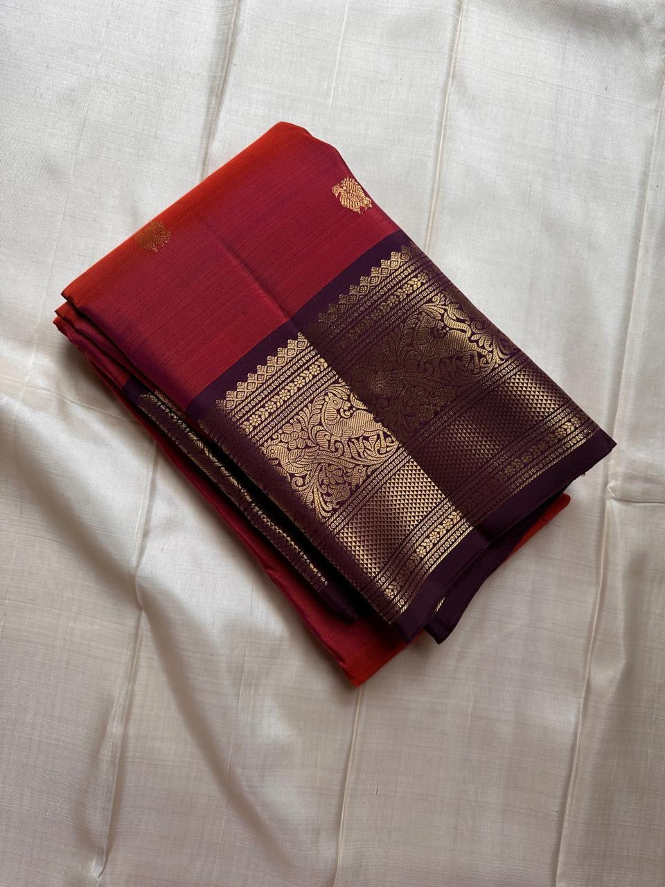 Shyama – Dusky Tangerine Kanchipuram Silk Saree with Purple Vanasringaram Border & Mayil Buttas