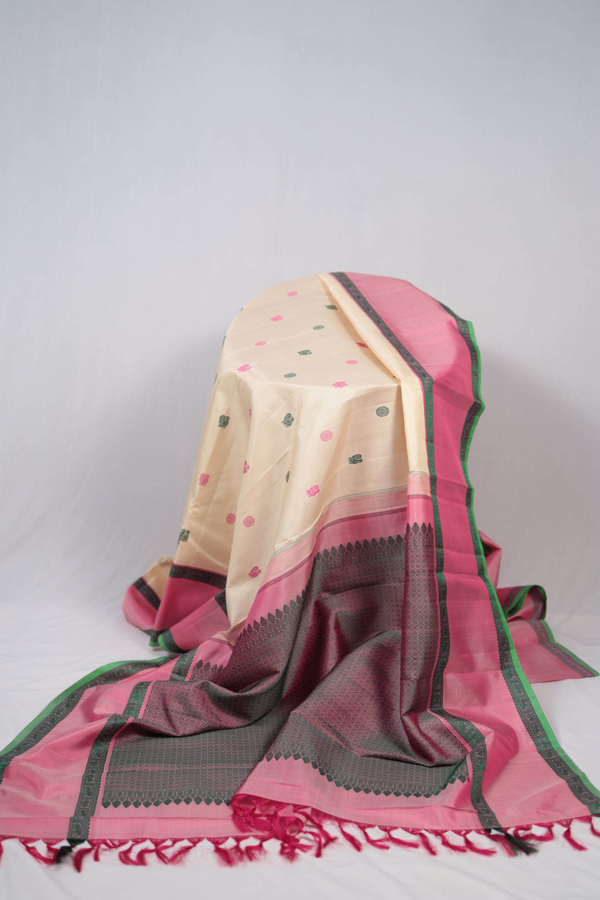 Full view of lotus pink bordered no-zari Kanchipuram silk saree with green silk-thread borders and tassels styled with décor
