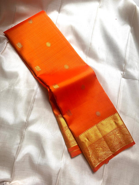 Agnika – orange Kanchipuram Silk Saree with Mayil Chakram Butta & Orange Border Fiery and regal, Agnika is a pure Kanchipuram silk saree featuring a rich red body adorned with intricate Mayil Chakram buttas.