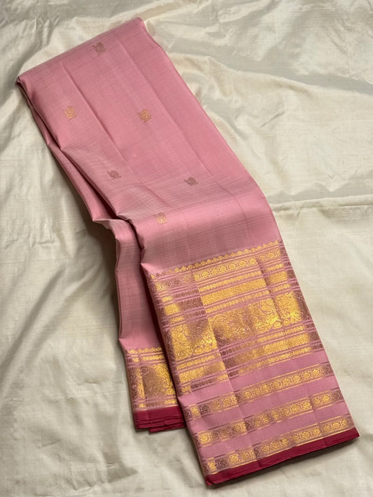 Folded blush pink Varisaipet Kanchipuram silk saree showing the rich gold zari pallu