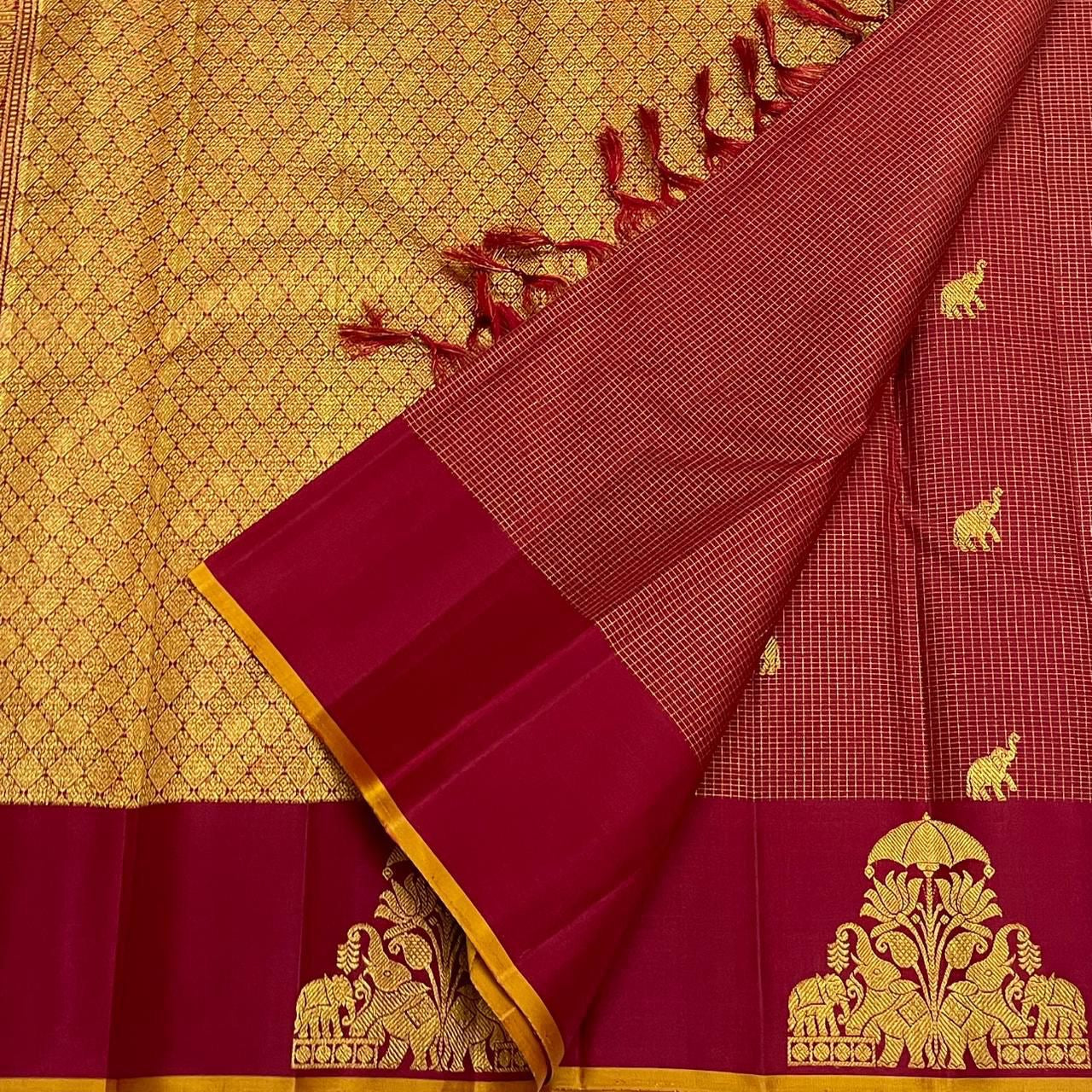 Close-up of maroon zari kattam saree with wine border and gold thiruvizha motif beside the gold zari pallu panel.