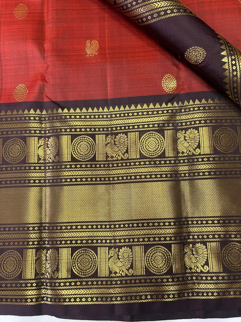 Aruna Mayil – Pure Korvai Kanchipuram Silk Saree

Brick red body with zari rosette buttas

Grand coffee-brown korvai border & pallu with peacock panels, medallions & temple teeth in rich gold zari

Silk Mark Certified | Blouse Piece Included | Fall & Pico