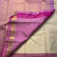 Close view of saree pallu in magenta-lavender with dense gold zari woven pattern, beside the cream body and border.