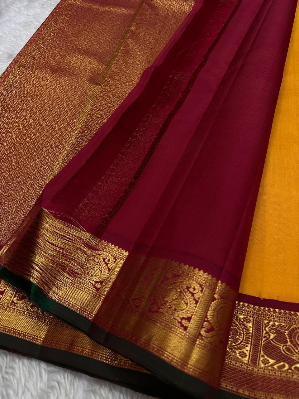 Saffron Royale – Pure Kanchipuram Silk Saree with Peacock Motif Border
Majestic saffron body with delicate zari buttas.
Rich maroon border woven with grand peacock motifs in  zari.
Traditional maroon pallu. Silk Mark Certified, delivery in 2 weeks