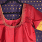 Red blouse with gold embroidery on a purple fabric background