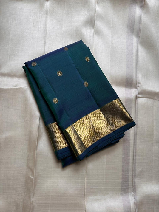 Folded peacock teal Kanchipuram silk saree with gold zari buttas and wide zari woven border