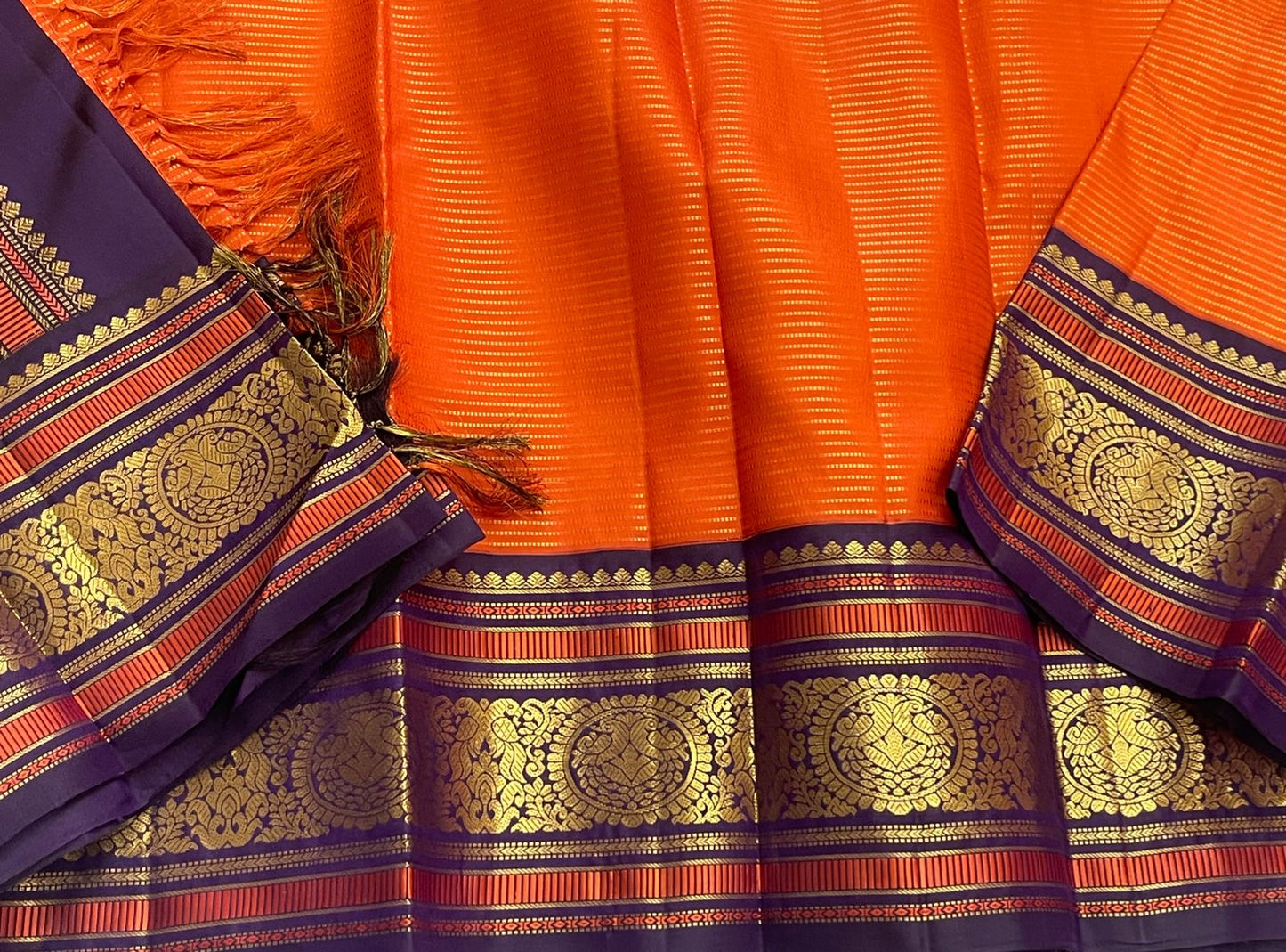 Kesari Annapakshi Chakram
Pure Kanchipuram Silk Saree – Vibrant Kesari Orange Body with Gold Zari Chakram Buttas
Deep Purple Korvai Borders with Majestic Annapakshi & Floral Motifs
Grand Purple Zari Pallu. Silk mark certified , ships in 2 weeks
