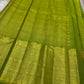A radiant parrot green Kanchipuram silk saree that dazzles. The body features a delicate grid-like zari weave with small gold buttas scattered. The rich gold zari pallu stands out with grand temple-inspired arches and intricate motifs.