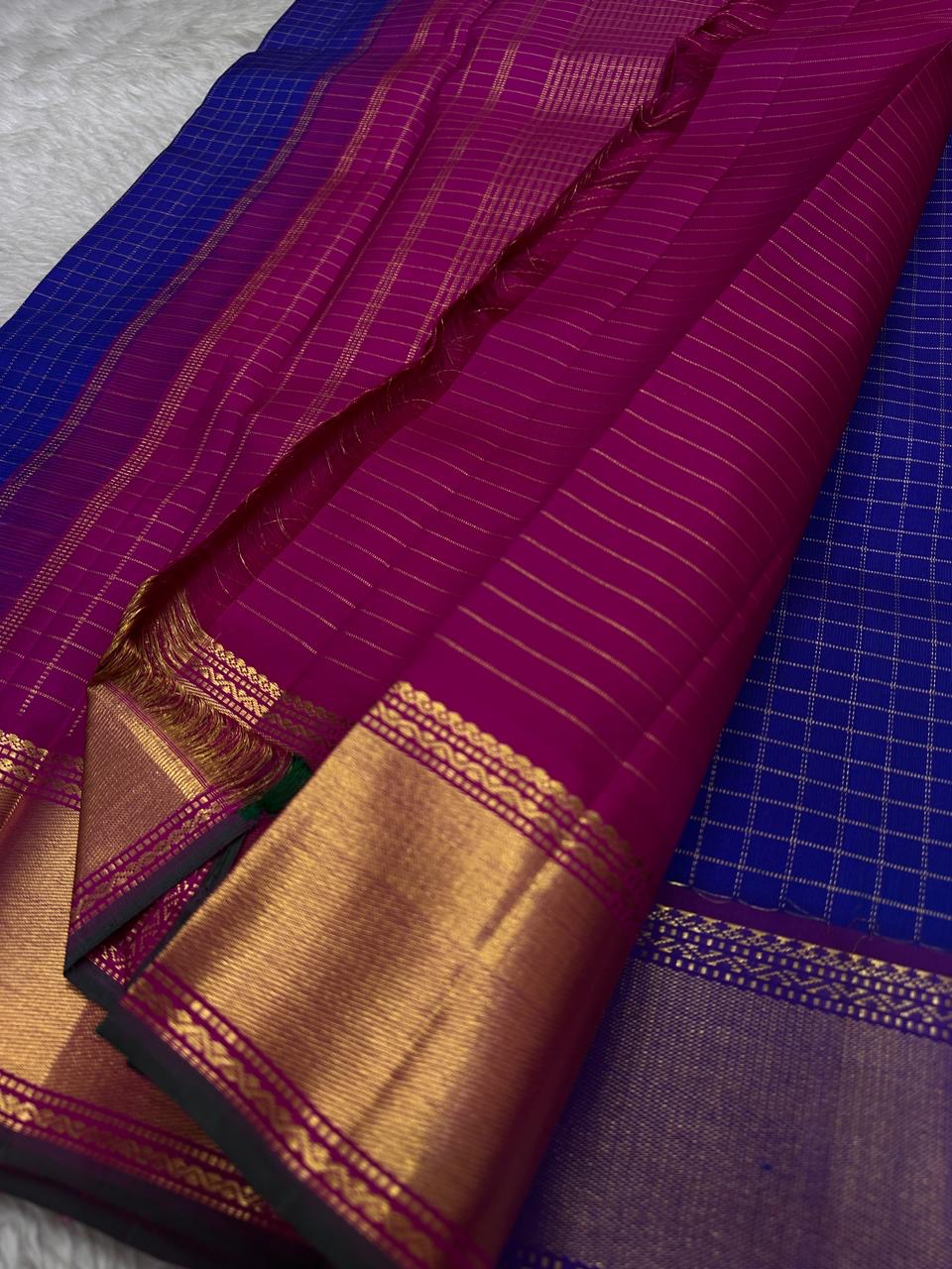 Sapphire Zari Kattam – Pure Kanchipuram Silk Saree
Brilliant Sapphire Blue Body with Gold Zari Checks
Broad Golden Border with Magenta Highlights & Temple Motifs
Royal Magenta Pallu with Lustrous Zari Stripes

Silk Mark Certified, delivery in 2 weeks