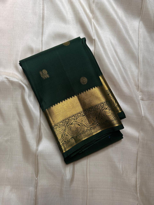 Agnika – Green Kanchipuram Silk Saree with Mayil Chakram Butta
Fiery and regal, Agnika features a rich green silk body with intricate Mayil Chakram (peacock) motifs and a shimmering zari border—an elegant ode to South Indian tradition.