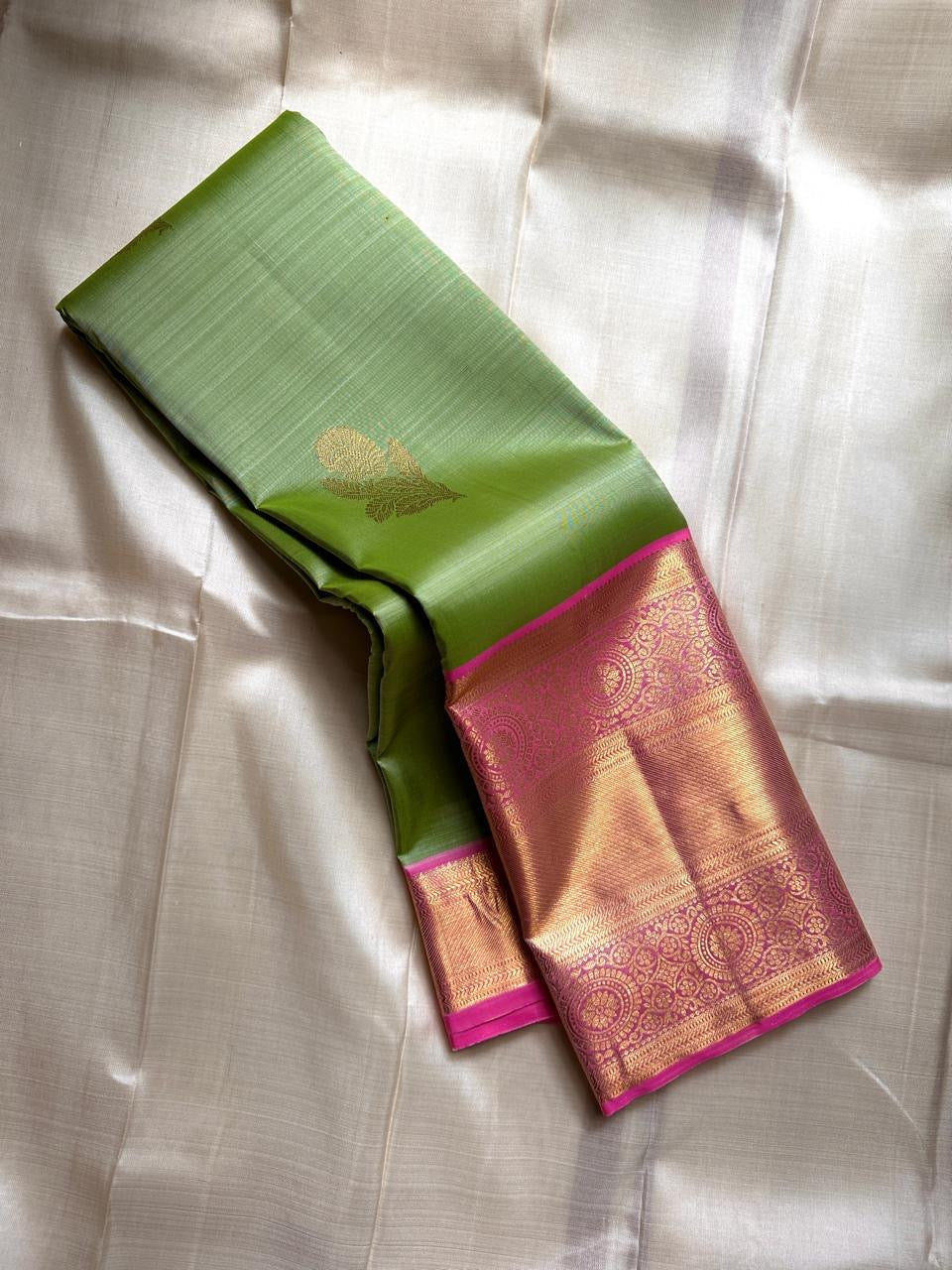 Spring green Kanchipuram silk saree with pink zari woven border and gold buttas, draped view