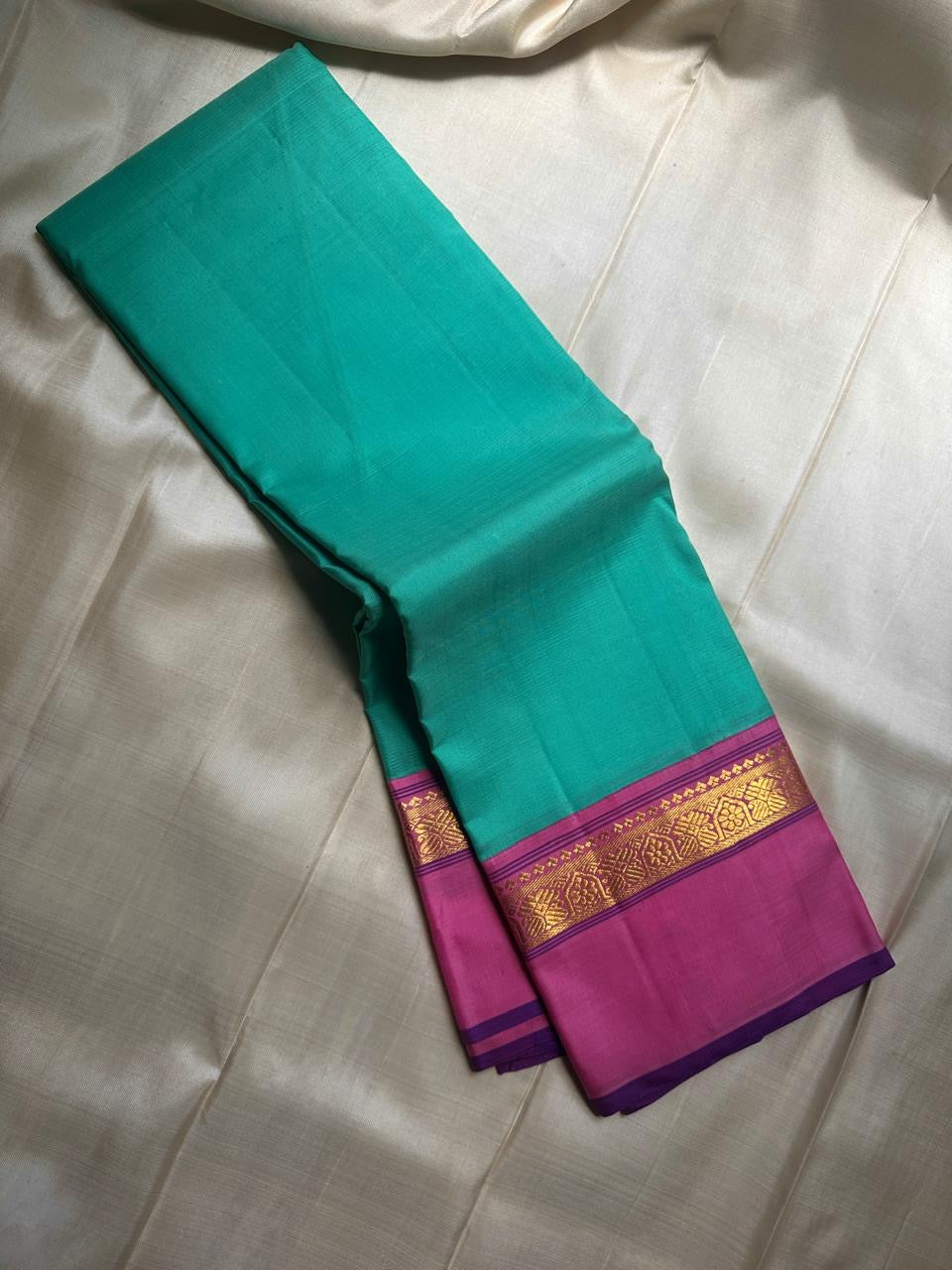 Jade Blossom – Pure Silk Kanchipuram Saree
Elegant Jade-Teal Body with Lustrous Weave 🌿
Rani-Magenta Contrast Border with Gold Zari ✨ purple selvedge 
Grand Magenta Pallu in Lattice Design
Silk Mark Certified | ships in 2 weeks