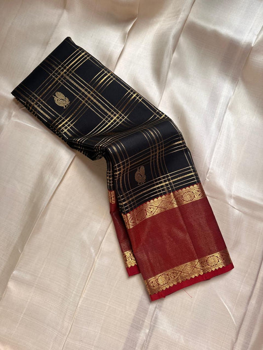 Kanmani Karuppu Kattam Ruby – Pure Kanchipuram Silk Saree
Deep black body with gold kattam checks & peacock buttas
Contrast ruby-red korvai borders
Grand ruby-red pallu with floral & lattice zari motifs
Silk Mark Certified | ships in 2 weeks