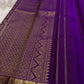 Stack of folded pure Kanchipuram silk sarees in multiple colors, including a teal saree with purple zari woven border.
