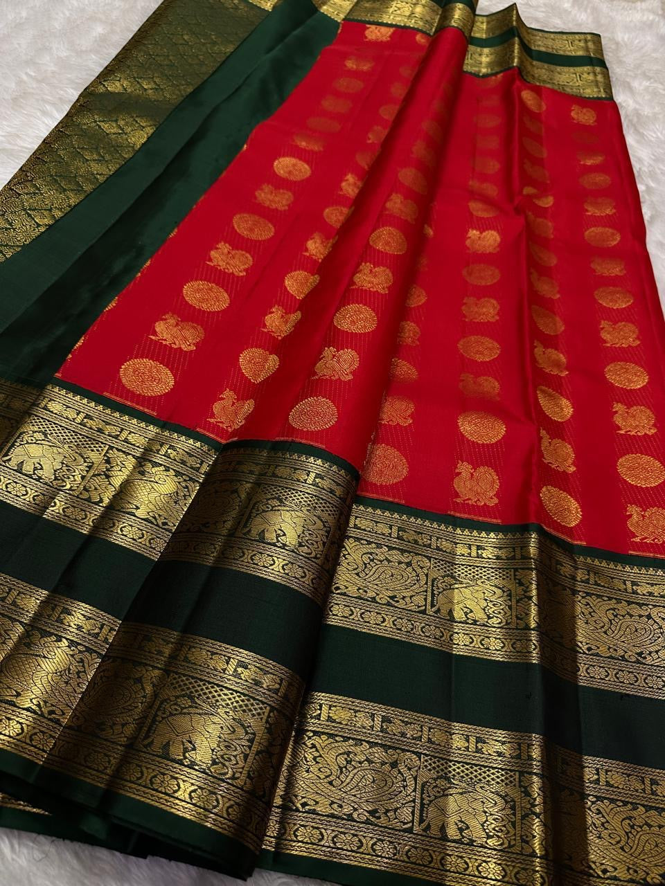 Full view of sindoor red Kanchipuram silk saree with gold buttas and temple-style green zari border