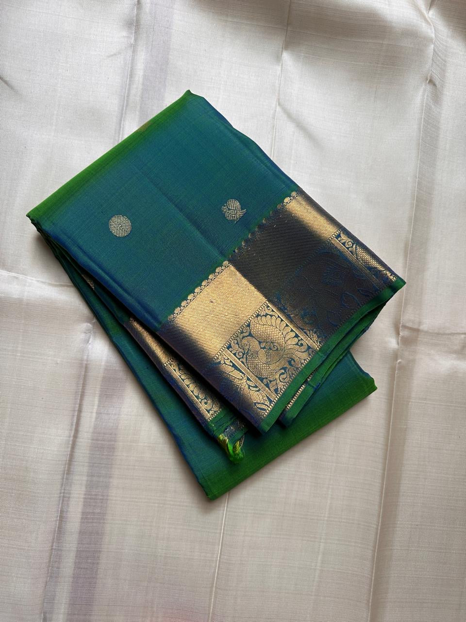 Dia ✨ – Vibrant Peacock Green Kanchipuram Pure Silk Saree
Gold Zari Buttas Adorning the Body
Intricate Gaja–Annam (Elephant & Peacock) Motif Border
Coordinated Peacock Green Silk Blouse Piece Included
Silk Mark Certified | Fall & Pico Done | Ready to Ship