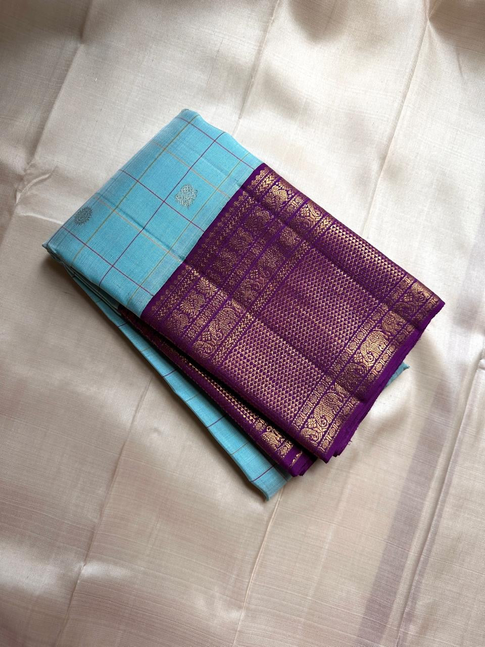Aakasa Kattam — Pure Kanchipuram Silk Saree
Sky-aqua body with fine kattam checks in lemon and violet, adorned with silver-zari paisley buttas and contrast purple brocade borders.
Silk Mark Certified • Free Shipping within USA • Dispatch in 1 Week • Ships