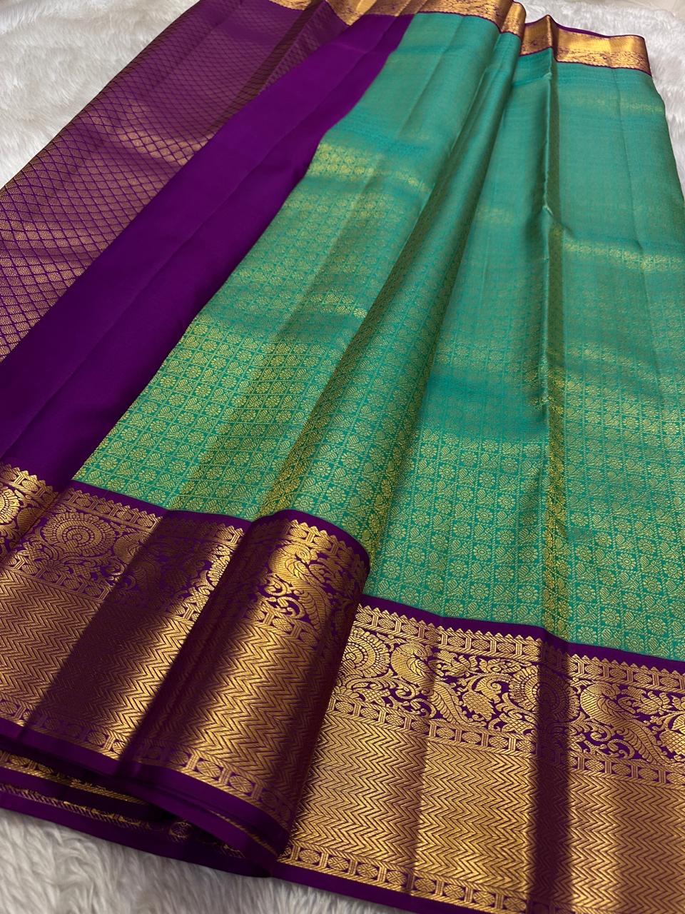 Sindhu- Teal & Purple Kanchipuram Pure Silk Saree with Floral Jaal & Mayil Border
A rich teal base adorned with delicate floral jaal and regal purple mayil borders creates timeless elegance. The diamond-motif pallu adds a bold, sophisticated finish to th
