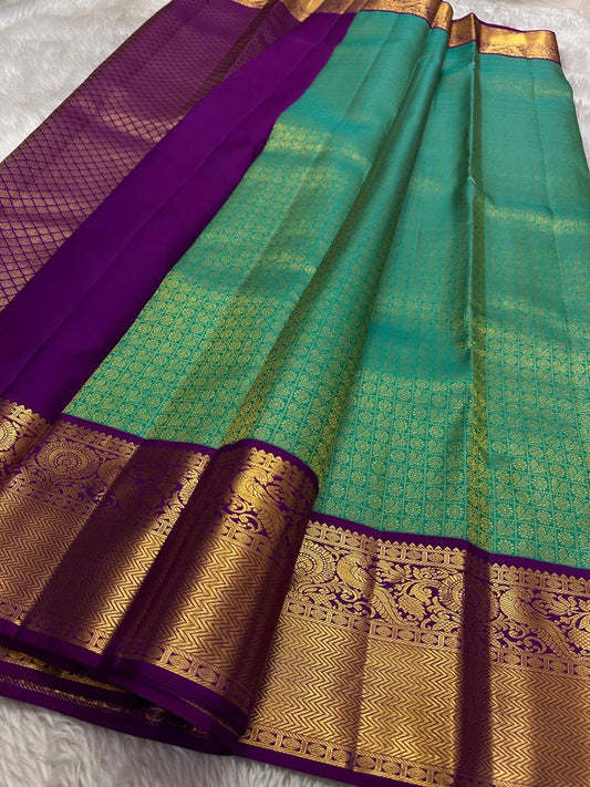 Sindhu- Teal & Purple Kanchipuram Pure Silk Saree with Floral Jaal & Mayil Border
A rich teal base adorned with delicate floral jaal and regal purple mayil borders creates timeless elegance. The diamond-motif pallu adds a bold, sophisticated finish to th