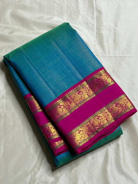 Kavi ✨ – Pure Kanchipuram Silk Saree
Teal Blue Silk Body with Lustrous Shot Weave
Rich Magenta Contrast Border in Gold Zari
Grand Pallu with Intricate Kili (Parrot) Motifs
Magenta Blouse with Matching Zari Border Silk Mark Certified, delivery in 2 weeks