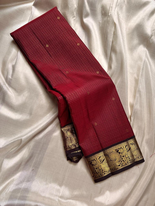 Mantra – Ruby Red coffee brown Kanchipuram Silk Saree with zari Checks with small buttas all over and Antique Peacock zari Border  showcasing regal peacocks and floral vines. A richly detailed pallu completes this heritage Zari kattam