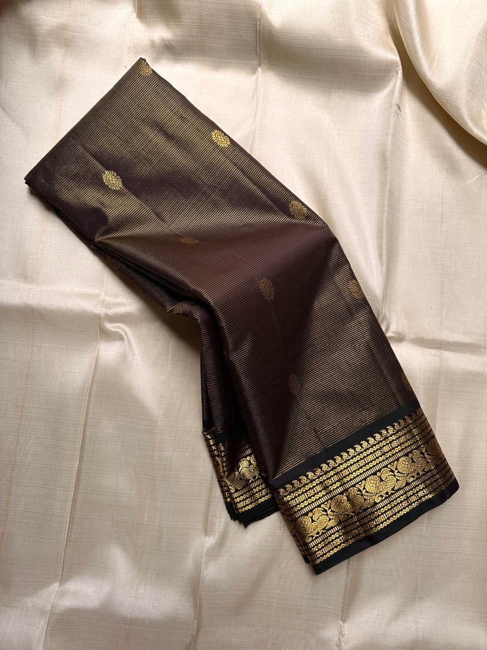 Kohl Swarna — silk mark certified lightweight saree 
Deep kohl brown body with fine pinstripes and gold rosette buttas, framed by antique-gold zari borders and grand paisley brocade pallu• free shipping eithin usa  two weeks