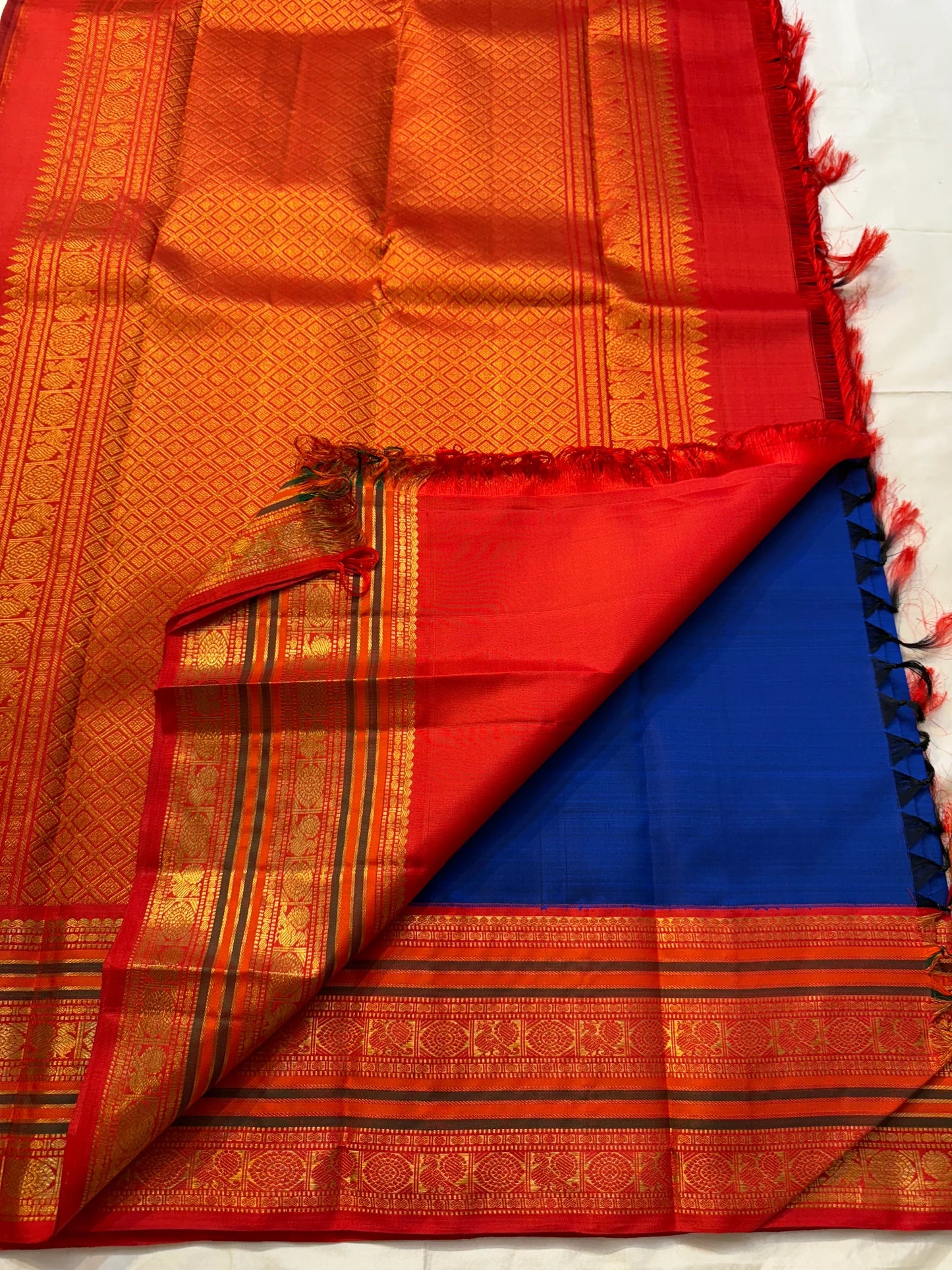 Kanchipuram silk saree pallu view with red-gold zari woven jaal and contrast blue section