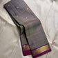 Varnam – Dove Tail Gray & Purple, a Kanchipuram silk saree where elegance meets bold expression. The soft dove tail gray base is adorned with vibrant magenta checks,Framed by a rich purple zari border and finished with an intricate contrast pallu
